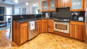 A modern kitchen with wooden cabinets, a stainless steel refrigerator, a built-in oven, and a black countertop. - Location! 1 Block from Bayshore / SOHO / Hyde Park (Tampa)