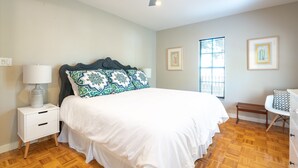A bedroom with a bed, nightstand, lamp, ceiling fan, window, and artwork on the walls. - Location! 1 Block from Bayshore / SOHO / Hyde Park (Tampa)