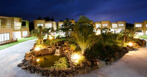 A modern hotel with multiple buildings, a landscaped garden with a pond, and a waterfall. - Ocean View Pension No. 2 (Jeju City)