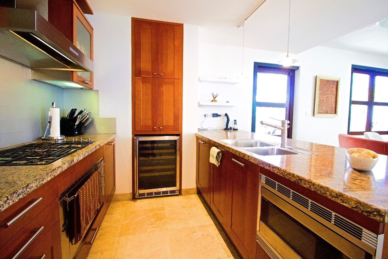 A kitchen with wooden cabinets, a built-in oven, a sink, and a countertop with a bowl.