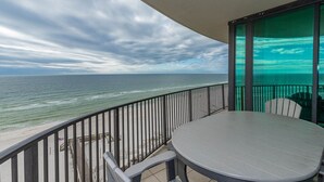 A balcony with a view of the ocean, a round table, and chairs. - ~ Premium 3BR @ Phoenix IX (Orange Beach)