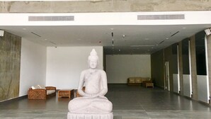 Um hall espaçoso com uma grande estátua de Buda, mobiliário moderno e teto alto com luminárias pendentes.