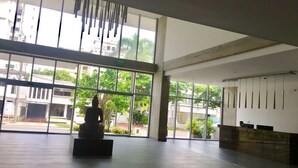Um hall amplo com grandes janelas, uma estátua de Buda e um balcão de recepção.
