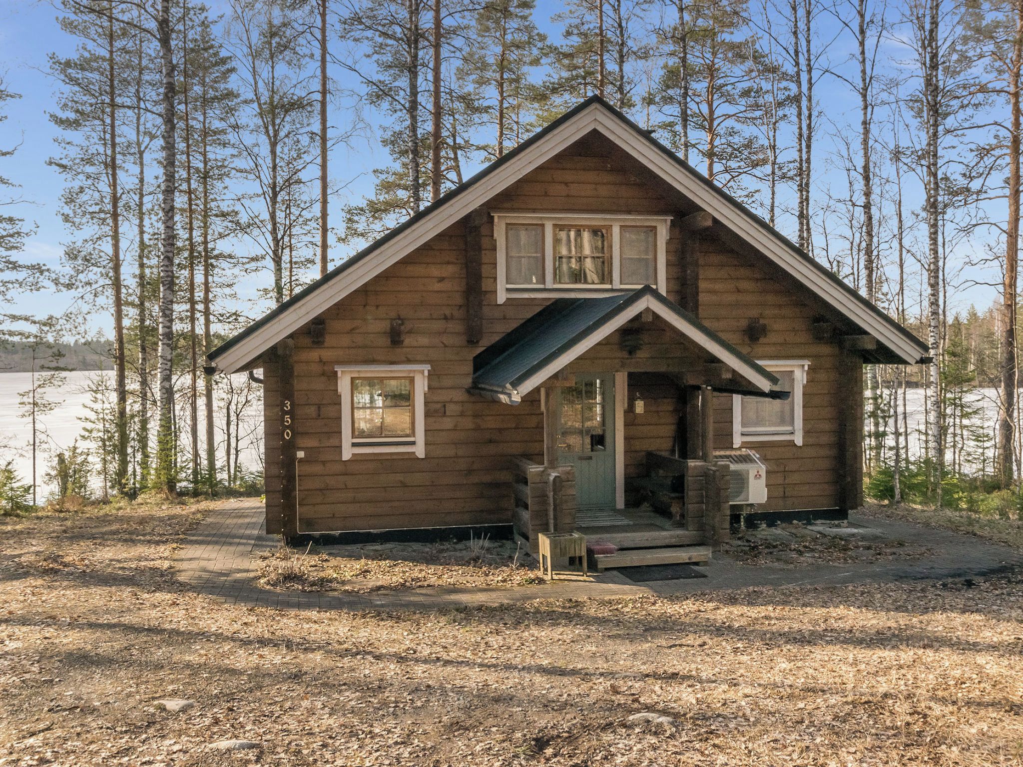 Une petite cabane en bois avec un toit à pignon, une véranda à l’avant et une cheminée bien visible.