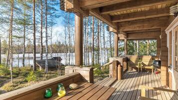 A wooden deck with outdoor seating and a view of a forest and lake.