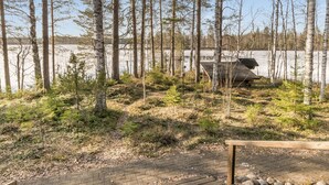 A forested area with a wooden deck and a view of a lake.