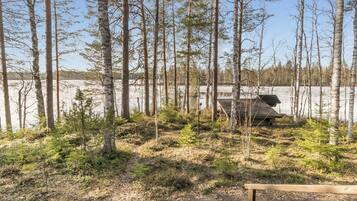 A forested area with a wooden deck and a view of a lake.
