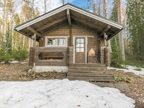 A wooden cabin with a front porch, a fireplace, and a door with glass panels.