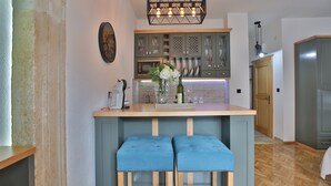 Een keuken met een centraal eiland, barstoelen, houten kastjes en een hanglamp.