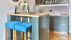 Een moderne keuken met een centraal kookeiland, barstoelen en een hangende lamp.