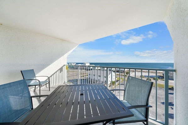 A balcony with a table and chairs, a railing, and a view of the ocean and buildings. - Coastal Getaway w/ Gulf & Lagoon Views | 2 Balconies | Boat-Friendly | Pool (Gulf Shores)