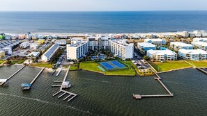 An aerial view of a coastal hotel with multiple buildings, a marina, and a tennis court.