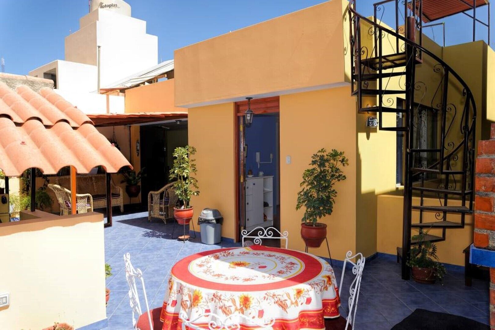 Un patio con una mesa redonda, plantas en macetas y una escalera de caracol.