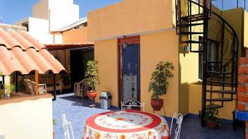 Un patio con una mesa redonda, plantas en macetas y una escalera de caracol.