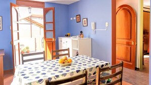 Un coin repas avec une table dressée pour deux personnes, un meuble blanc et une porte en bois.