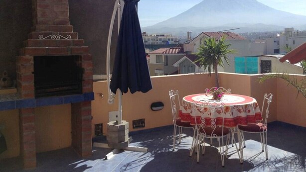 Une terrasse avec une cheminée en briques, une table avec des chaises et une vue sur une montagne.