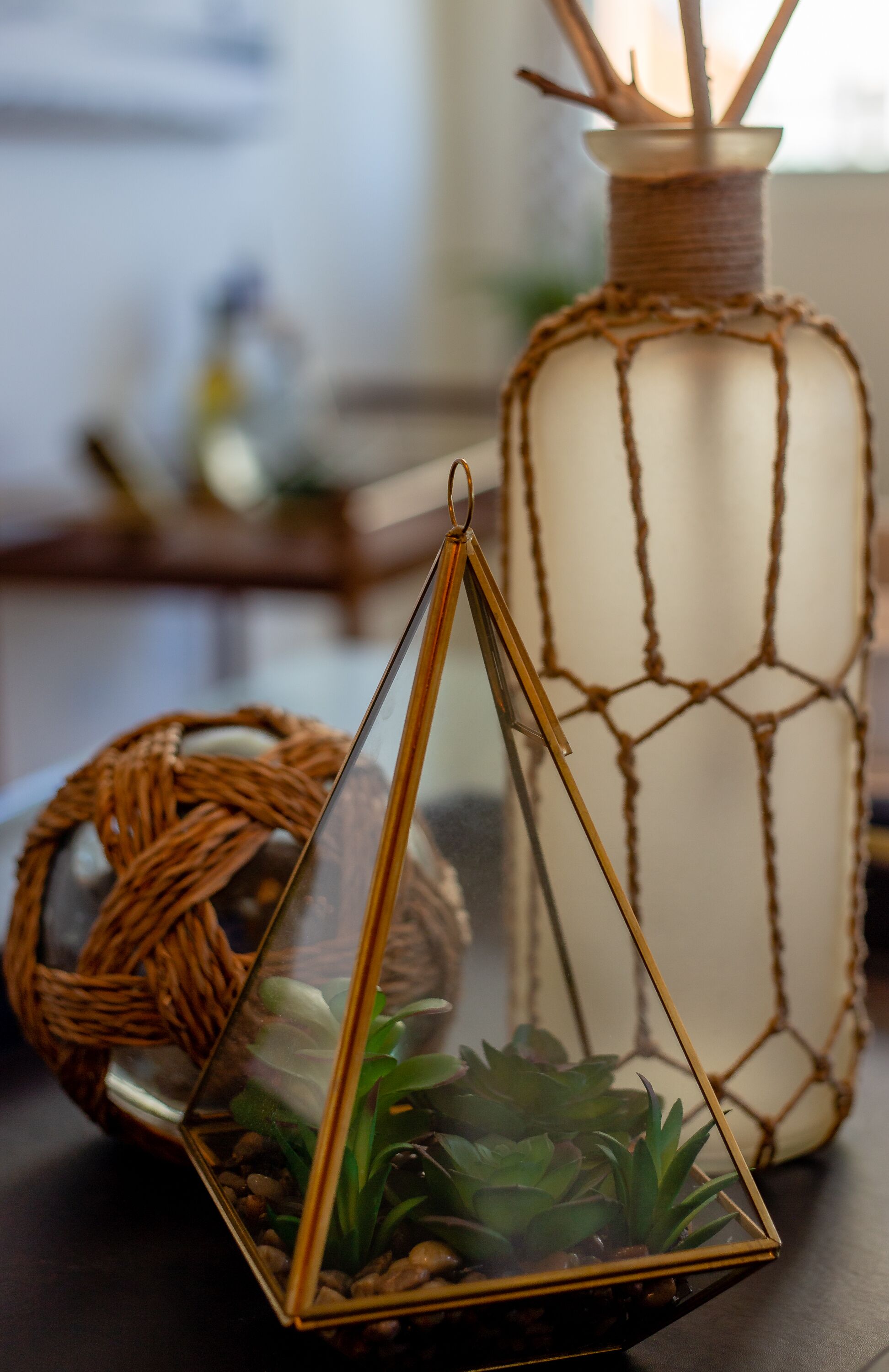 A glass terrarium with succulents, a woven basket, and a candle holder.