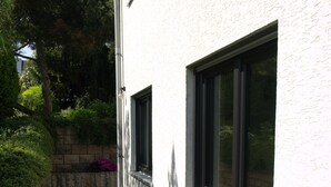 A narrow concrete pathway leading to a building with large windows and a white exterior wall. - Living comfortably in Oberwalluf, enjoying the Rheingau, experiencing the Rhine - Main! (Walluf)