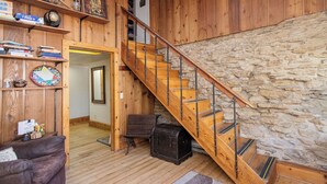 Ein Holzinnenraum mit einer Steinwand, einer Holztreppe und einer gemütlichen Sitzecke.