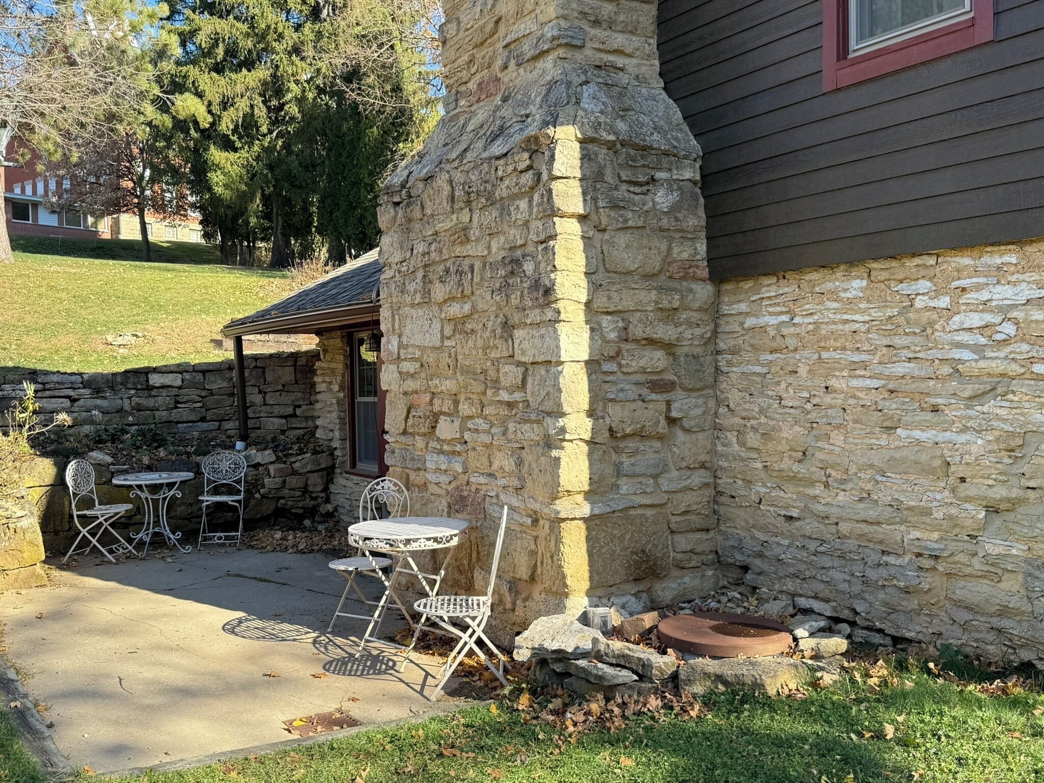 A stone patio with outdoor seating and a stone wall.