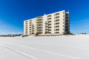 A multi-story hotel with balconies, located on a sandy beach. - Come stay at guest favorite-Salty Kisses on the Beach! (Pensacola Beach)