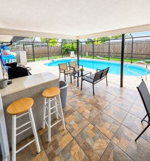 An outdoor patio with a pool, bar area, and seating.
