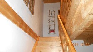 A wooden staircase with a handrail, a wall-mounted ladder, and a decorative item hanging on the wall. - Nice holiday home "Aunt Emma" in Regen, Bavarian Forest, pets welcome (Kattersdorf)