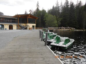 A wooden dock with several green and white boats moored at the end. There is a building with a yellow facade and a staircase leading to an upper level. - Nice holiday home "Aunt Emma" in Regen, Bavarian Forest, pets welcome (Kattersdorf)