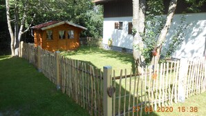 A wooden cabin with a red roof, surrounded by a wooden fence and trees. - Nice holiday home "Aunt Emma" in Regen, Bavarian Forest, pets welcome (Kattersdorf)