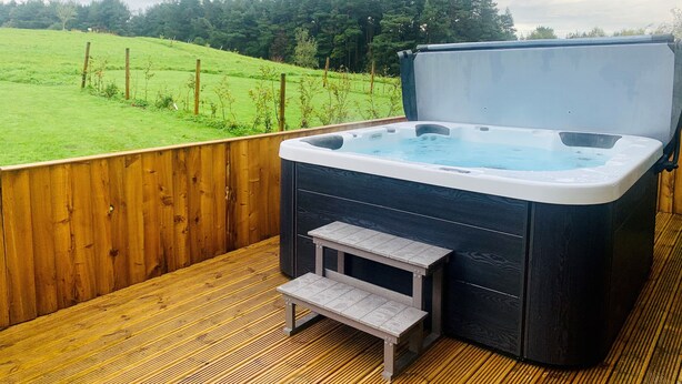 A hot tub on a wooden deck with a view of a green field and trees. - Brock Cottage private Hot Tub DOG/Cat FRIENDLY* with on site fishing (Pickering)