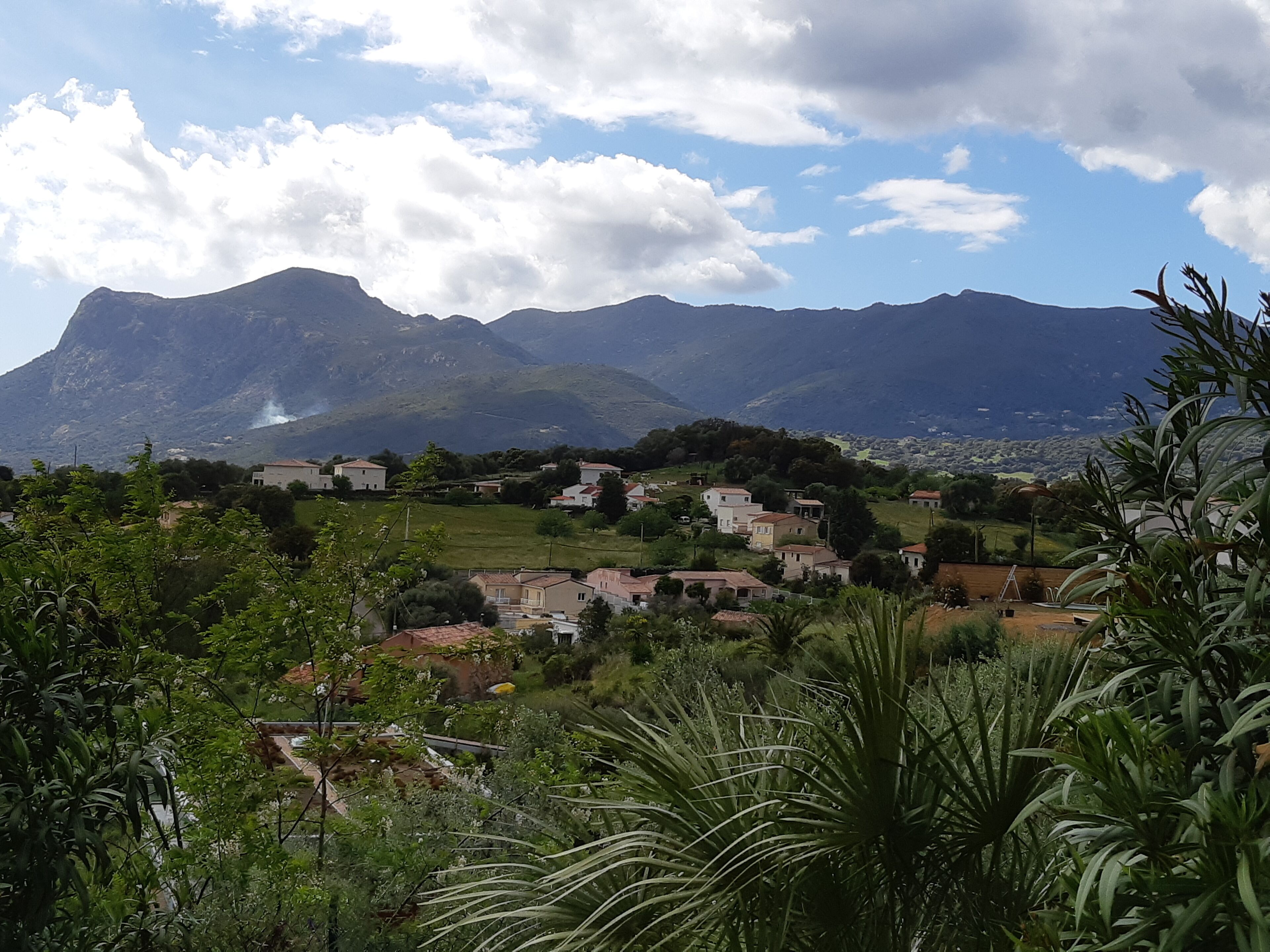 Un paysage montagneux avec un village au premier plan et une montagne imposante en arrière-plan.
