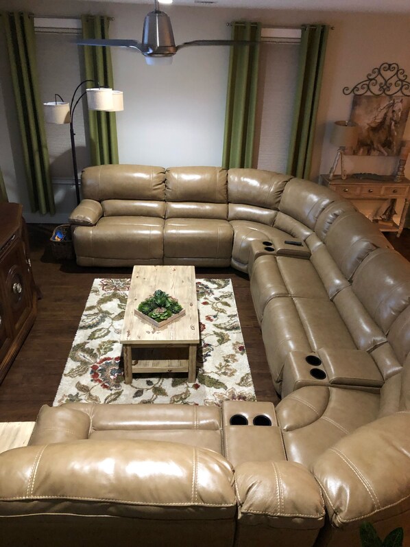 A L-shaped leather sectional sofa with a wooden coffee table in the center, a floor lamp, and a decorative wall piece. - Summertime Sweetness in St.Augustine- Close to Festival Locations & Downtown! (St. Augustine)