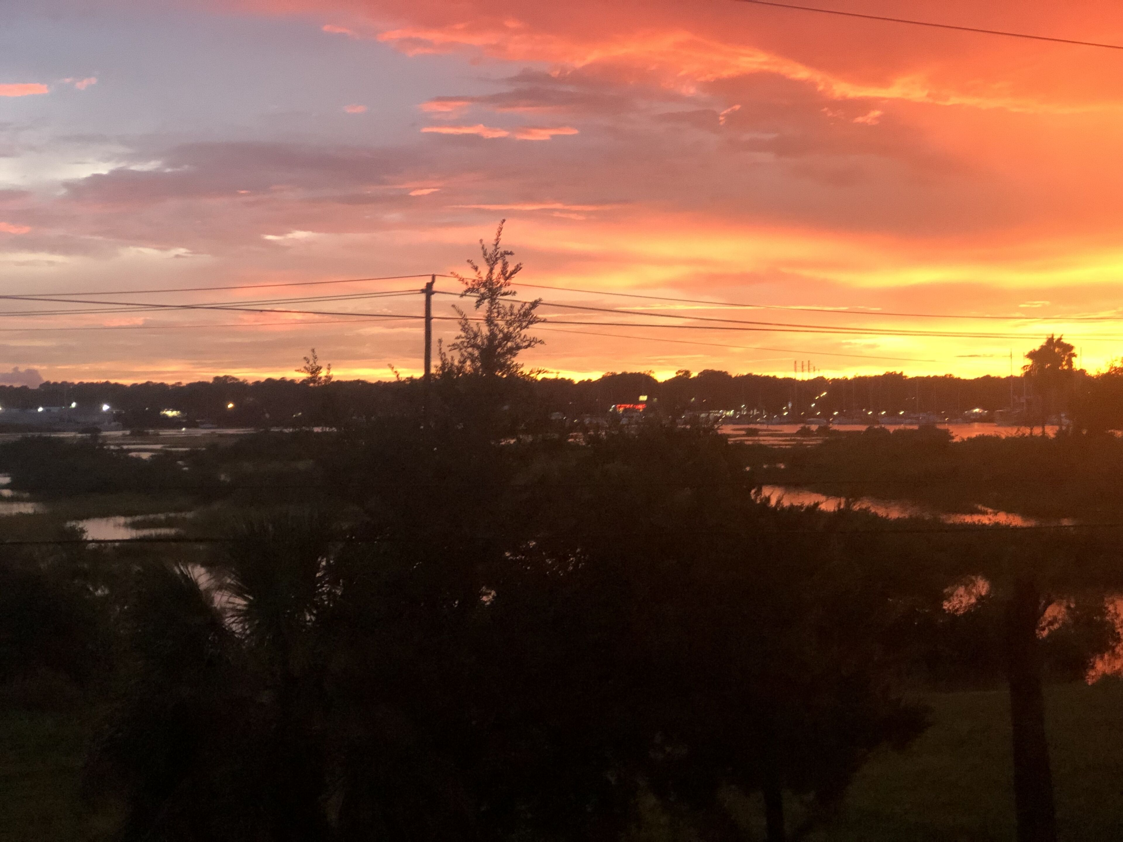 Auringonlasku maaseutumaisemassa, jossa on peltoja ja vesistö.