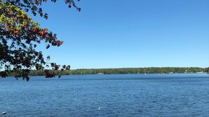 Une jetée en bois, avec une table et des chaises, d’où l’on peut admirer un lac paisible et une rive éloignée.