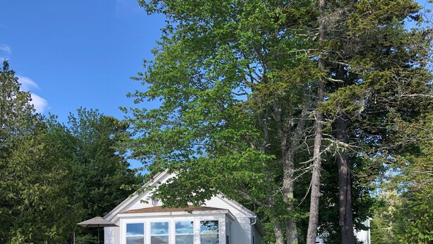 Un chalet au bord du lac, doté d’un quai, d’une terrasse avec mobilier d’extérieur et d’un muret en pierre longeant le rivage.