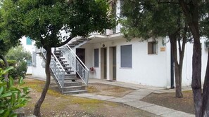 A building with a staircase leading to a door, surrounded by trees.
