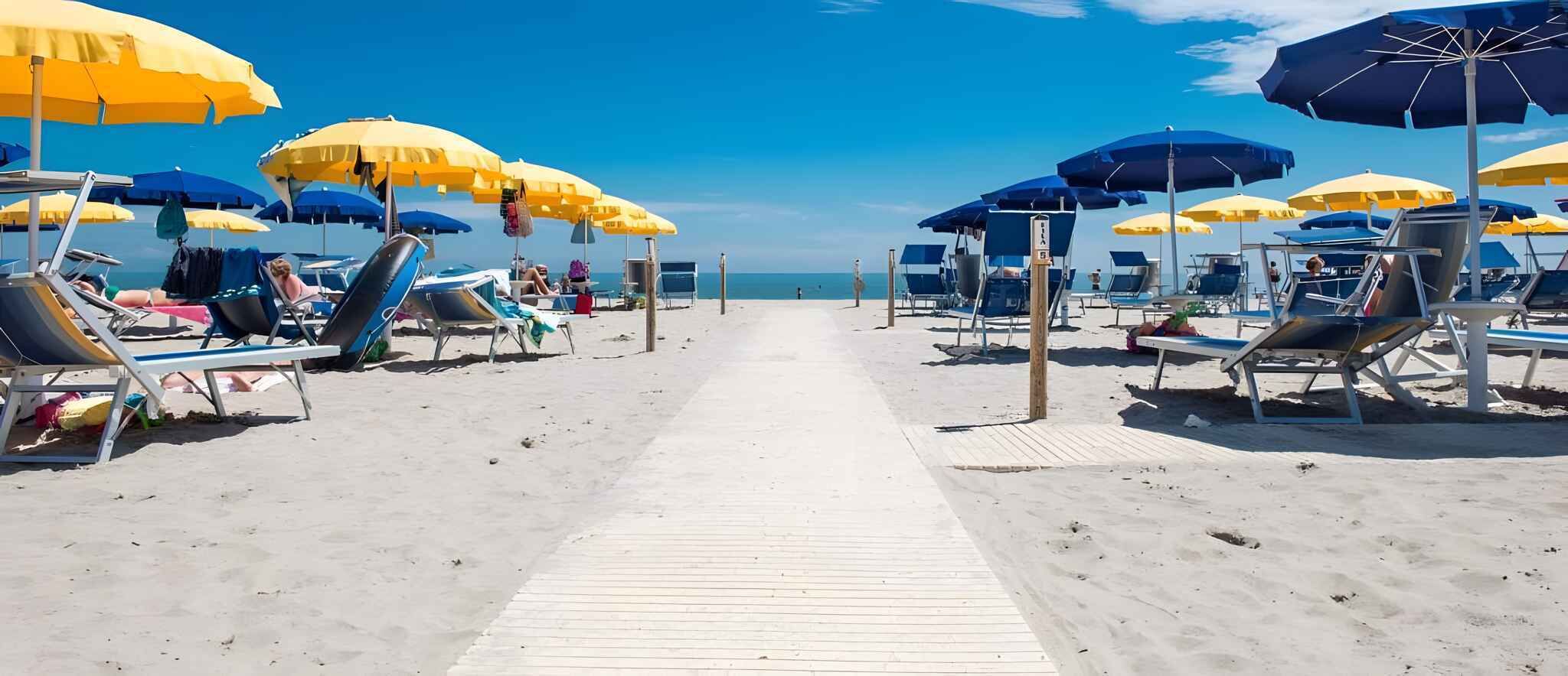 A beach with rows of sun loungers and umbrellas, a wooden walkway, and the ocean in the background.