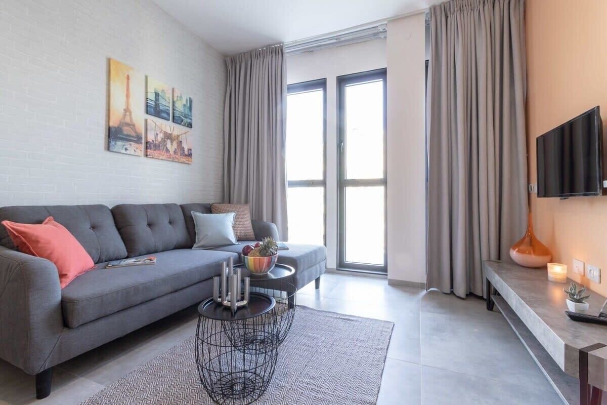 Ein modernes Wohnzimmer mit einem grauen Sofa, einem Couchtisch und einem Flachbildfernseher.