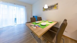 A dining area with a wooden table, chairs, and a hanging light fixture. - Lovely bright apartment, with modern design, perfect for families! (Bolzano)