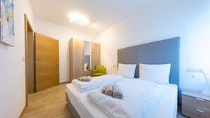 A modern hotel room with a large bed, a wooden wardrobe, a bright green chair, and a bedside table with a lamp. - Lovely bright apartment, with modern design, perfect for families! (Bolzano)
