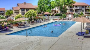 A swimming pool with lounge chairs and umbrellas, surrounded by apartment buildings. - Athlete, Family, and Pet Friendly - Something for everyone! (St. George)