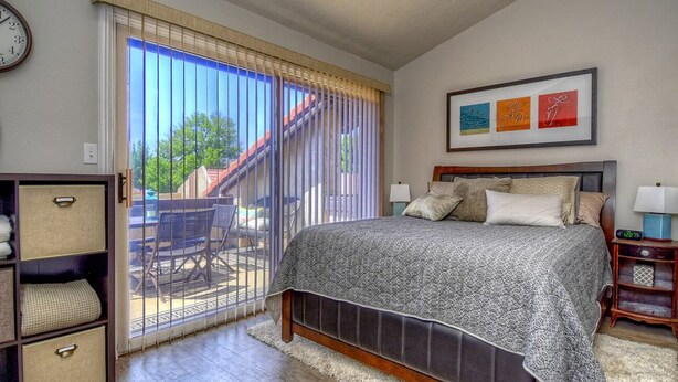 A bedroom with a bed, a nightstand, a lamp, a clock, and a sliding door leading to a balcony. - Athlete, Family, and Pet Friendly - Something for everyone! (St. George)