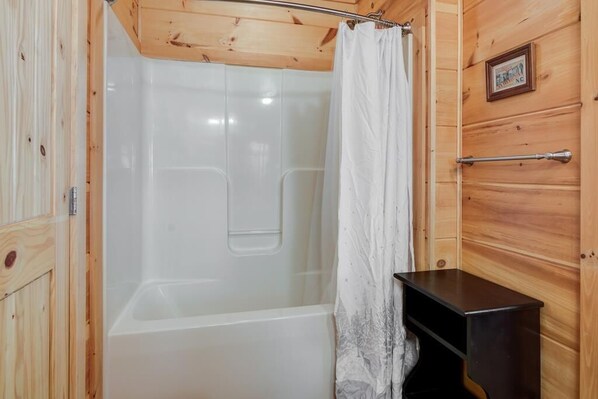 A wooden cabin bathroom with a shower, a towel rack, and a small wooden cabinet.