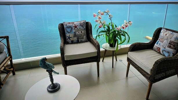 Ein Balkon mit Korbstühlen, einem kleinen Tisch und einem Topf mit einer Orchideenpflanze.