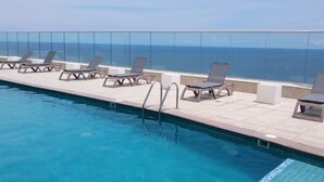 Ein Poolbereich mit Liegestühlen und Meerblick.