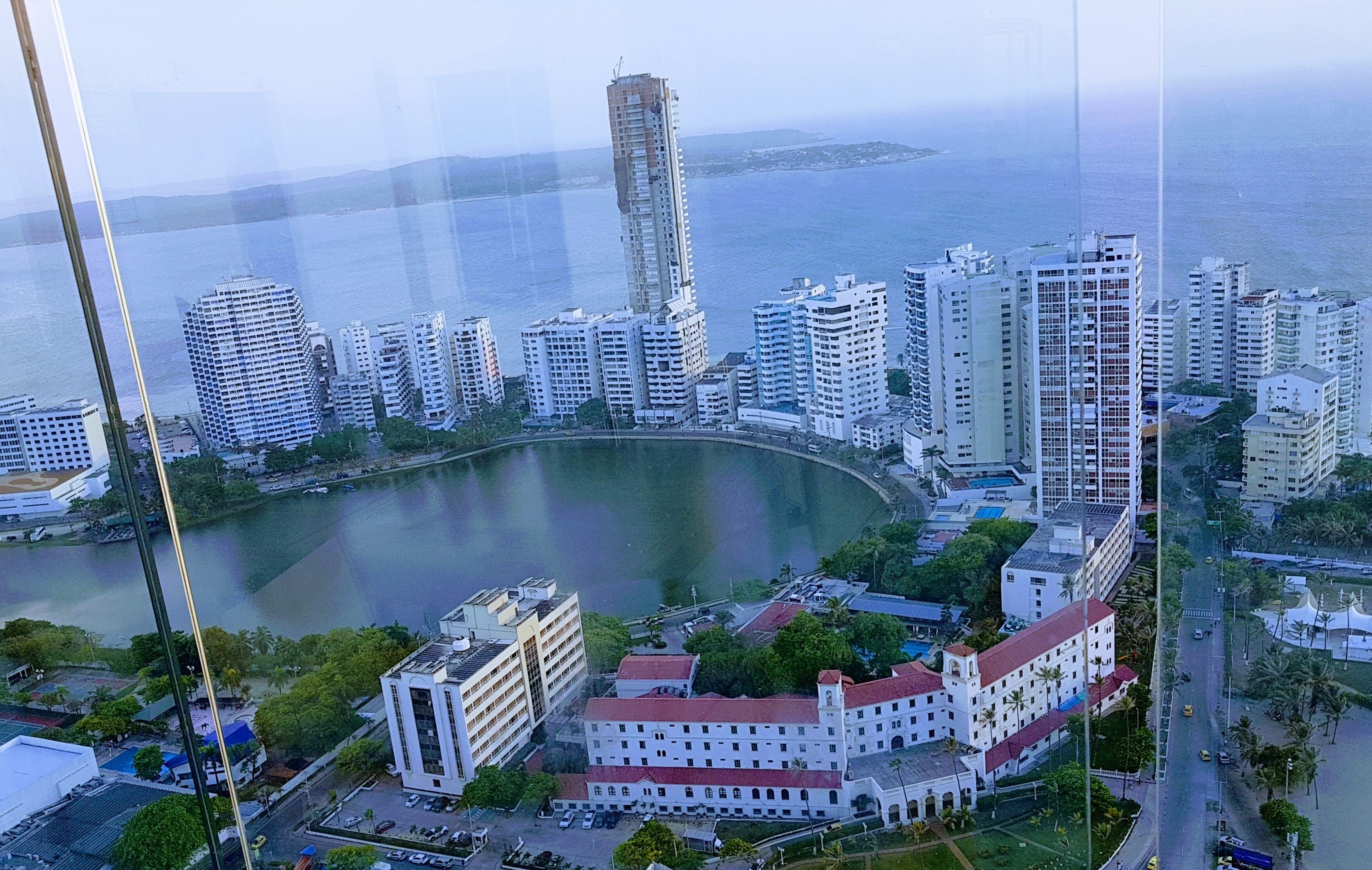 A coastal cityscape with high-rise buildings, a central roundabout, and a body of water.