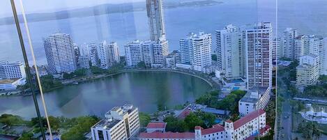 A coastal cityscape with high-rise buildings, a central roundabout, and a body of water.