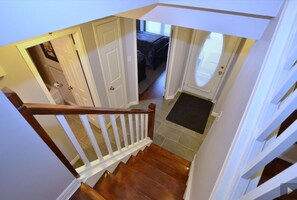 A staircase leading to a bedroom with a door, a window with blinds, and a small rug at the base.