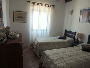 Una camera da letto con due letti, una cassettiera in legno e una finestra con tende.