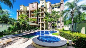 Un hotel con piscina, palmeras y un edificio de varios pisos.